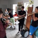 Trójka młodych chłopców grających na instrumentach dętych.