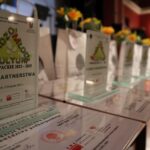 Stojące na brzegu sceny w sali widowiskowej statuetki dla beneficjentów BMK